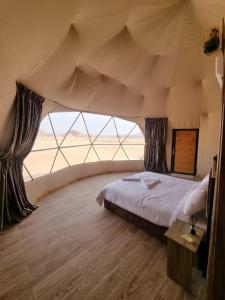 a bedroom with a bed and a large window at Rum Magic Desert in Wadi Rum