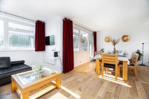 ein Wohnzimmer mit einem Sofa und einem Tisch in der Unterkunft Lit & airy 2BR Flat wparking & balcony, Wimbledon in London