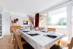 a dining room with a table with chairs and a large window at Lit & airy 2BR Flat wparking & balcony, Wimbledon in London