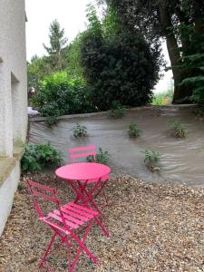 zwei rosa Stühle und ein roter Tisch im Hof in der Unterkunft L’appart Quessoy in Quessoy