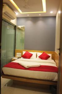 a bedroom with a large bed with red pillows at MAROL METRO HOTEL MUMBAI in Mumbai