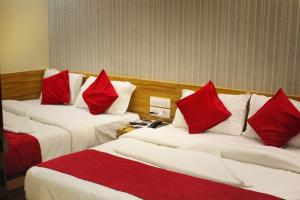 Habitación de hotel con 2 camas con almohadas rojas en MAROL METRO HOTEL MUMBAI, en Bombay