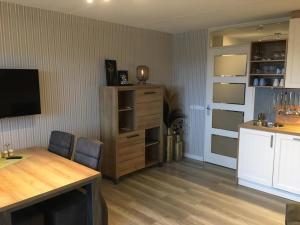 a living room with a table and a tv and a kitchen at Amelander Paradijs Ferienwohnung in Buren