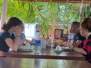 Talalla Ocean Beach Bungalow في ماتارا: مجموعة من الناس يجلسون على طاولة يأكلون الطعام