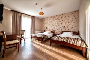1 dormitorio con 2 camas, escritorio y mesa en Hotel Pan Tadeusz en Osielsko