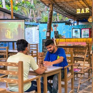 two men sitting at a table in a restaurant at Traverse Luxe Hostel Palolem in Palolem