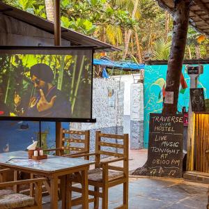 a stage with a table and chairs in front of a screen at Traverse Luxe Hostel Palolem in Palolem