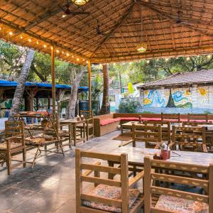 a restaurant with wooden tables and chairs and a mural at Traverse Luxe Hostel Palolem in Palolem