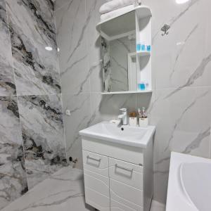 a white bathroom with a sink and a mirror at Jetysu2 in Prigorodnyy