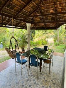 a table and chairs on a patio with a swing at Thoppil Homestay Munnar in Munnar