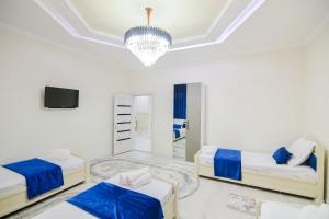 Habitación blanca con 2 camas y lámpara de araña. en Cozy Two-Storey House en Bukhara
