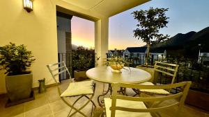 een tafel en stoelen op een balkon met uitzicht op de zonsondergang bij Le Bourgette in Franschhoek
