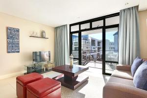 a living room with a couch and a table at Eden On The Bay 118 by HostAgents in Bloubergstrand
