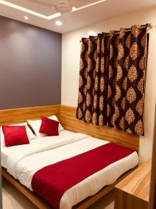 a bedroom with a large bed with red pillows at MAROL METRO HOTEL MUMBAI in Mumbai