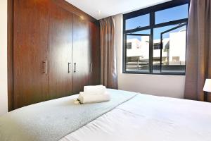 a bedroom with a large white bed with a window at Eden On The Bay 118 by HostAgents in Bloubergstrand