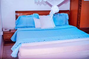 Cama azul con almohadas azules y blancas en SILVER HOTEL APARTMENT Near Kigali Convention Center 10 minutes, en Kigali