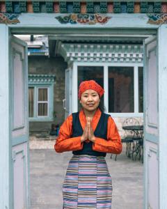 uma mulher à frente de uma porta com as mãos à frente em Mountain Lodges of Nepal - Namche em Namche