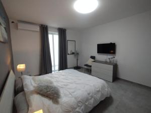 um quarto com uma cama branca e uma televisão em San Pawl Lodge Hostel em St Paul's Bay