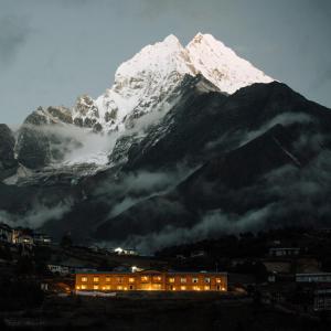 a snow covered mountain with a building in front of it at Mountain Lodges of Nepal - Namche in Namche