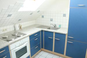 uma cozinha com armários azuis e um lavatório em Ferienwohnung am Bio-Bauernhof em Obertrum am See