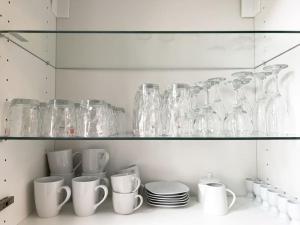 a shelf filled with glass vases and cups and plates at Exklusives Leipzig City Apartment Flowers in Leipzig