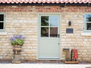 een stenen huis met een witte deur en bloemen bij 1 Bed in Kirkby Green 94133 