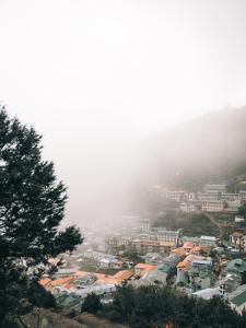 eine Stadt auf einem nebligen Hügel mit Häusern und Gebäuden in der Unterkunft Mountain Lodges of Nepal - Namche in Namche