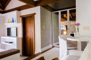 a living room with a table and a white room at Solar Mirador Exclusive Resort e SPA in Praia do Rosa