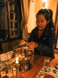 Una donna seduta a un tavolo con una candela di Mountain Lodges of Nepal - Namche a Namche