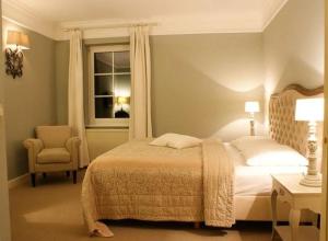 a bedroom with a bed and a chair and a window at Schloss Krugsdorf Golf & Hotel in Krugsdorf