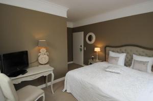 a bedroom with a bed and a tv and a chair at Schloss Krugsdorf Golf & Hotel in Krugsdorf