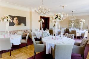 a dining room with white tables and chairs and chandeliers at Schloss Krugsdorf Golf & Hotel in Krugsdorf +265 photos