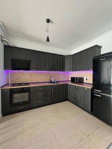 une cuisine avec des armoires noires et un éclairage violet dans l'établissement Lakeside Oasis Apartment, à Bucarest