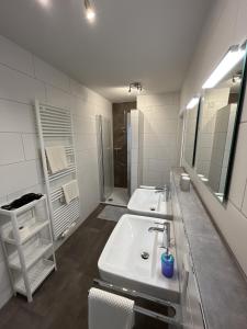 a white bathroom with two sinks and a shower at Seeblick in Versmold