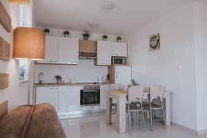 a kitchen with white cabinets and a table and chairs at Poolside Hideout Apartments in Novalja