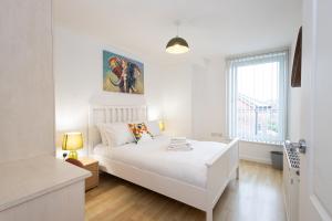a white bedroom with a white bed and a window at Withington Apartments- Wilmslow Road- Free Parking in Manchester