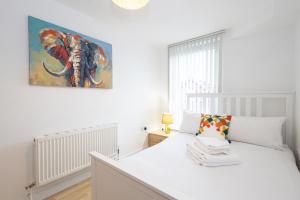 - une chambre avec un lit blanc orné d'une peinture murale dans l'établissement Withington Apartments- Wilmslow Road- Free Parking, à Manchester