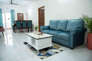 a living room with a blue couch and a table at Yellow Bells Serviced Apartments Hitech City in Hyderabad