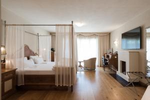 a bedroom with a canopy bed with a desk and a chair at Preidlhof Luxury Dolce Vita Resort in Naturno