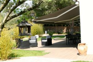 un patio con cenador, sillas y mesa en la villa d'Ariane-piscine-jaccuzi-15 mn Mer, en Vendargues