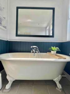 La salle de bains est pourvue d'une baignoire blanche et d'un miroir. dans l'établissement Luxury 4 bedroom house in London featured on TV, à Londres
