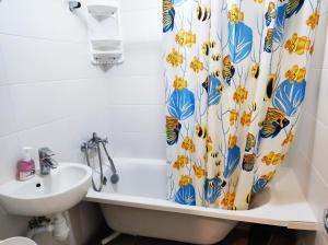 y baño con bañera, lavamanos y cortina de ducha. en Новая квартира апартаменты в центре, en Izmaíl