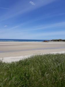a beach with grass and the ocean in the background at karluchi a Mariña 2 Barreiros in Barreiros