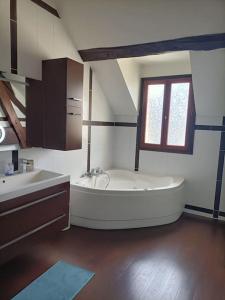 a large white bathroom with a tub and a sink at Belle maison du 18e siècle in Bazemont