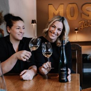 two women sitting at a table with wine glasses at Hotel-Restaurant Peifer in Brodenbach