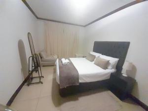 1 dormitorio con 1 cama y 1 silla en Cedar Fourways Sandton en Trevallyn