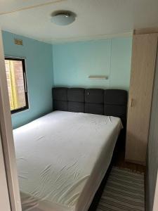 een bed in een kamer met een blauwe muur bij Stacaravan aan het “Drents Friese Wold”. in Elsloo