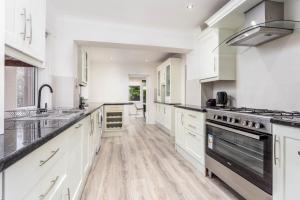 a large white kitchen with white cabinets and appliances at Cuthbert House in Prestwick