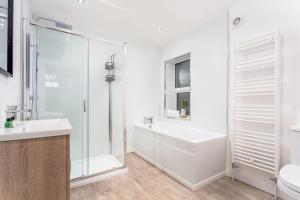 Baño blanco con bañera y lavamanos en Cuthbert House, en Prestwick