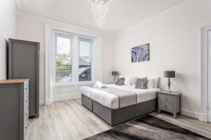 a white bedroom with a bed and a window at Cuthbert House in Prestwick